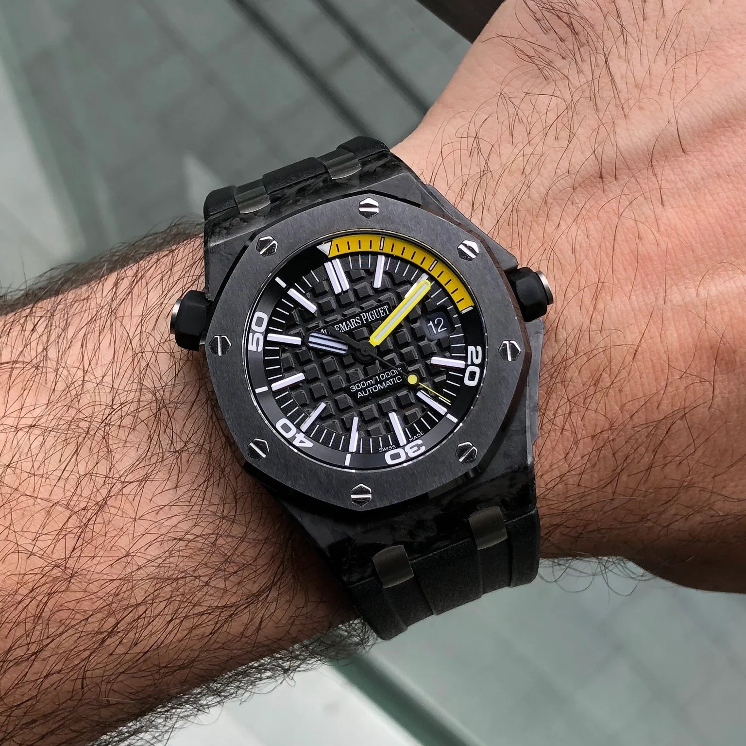 Black watch with yellow accents on a wrist against a blurred background