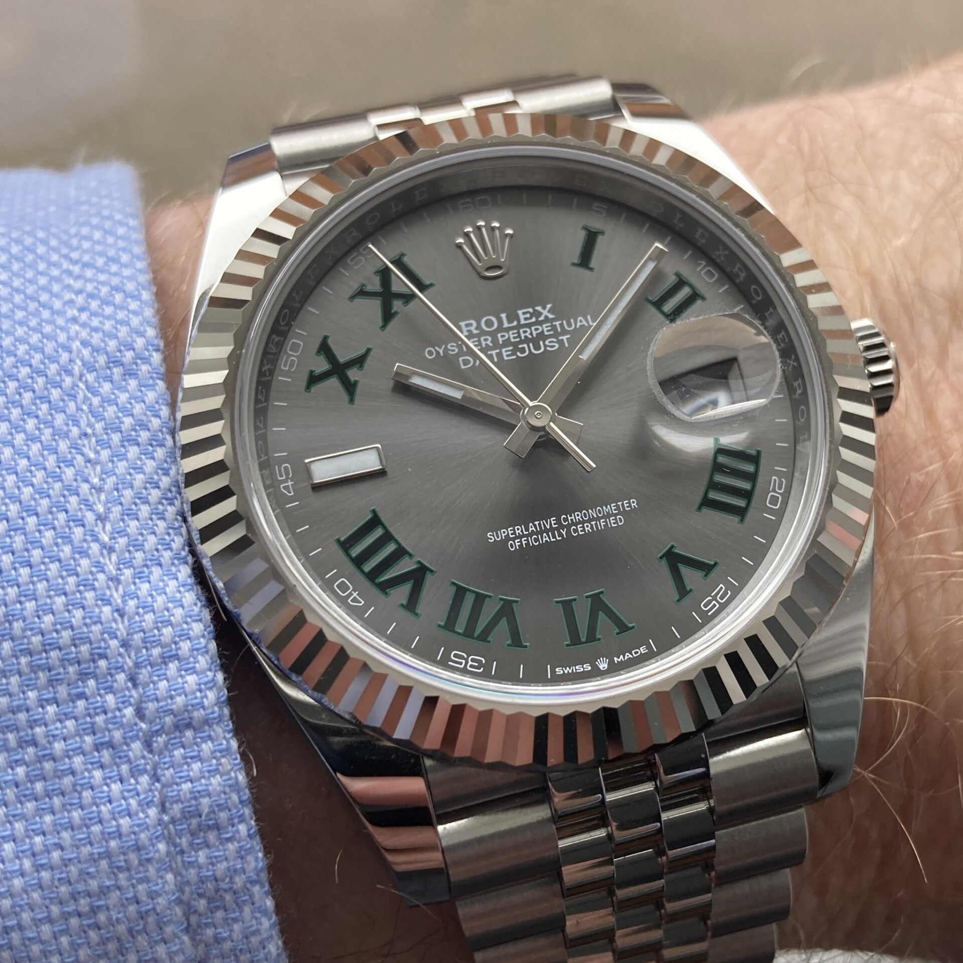 Silver watch with a gray face and Roman numeral markers on a wrist.