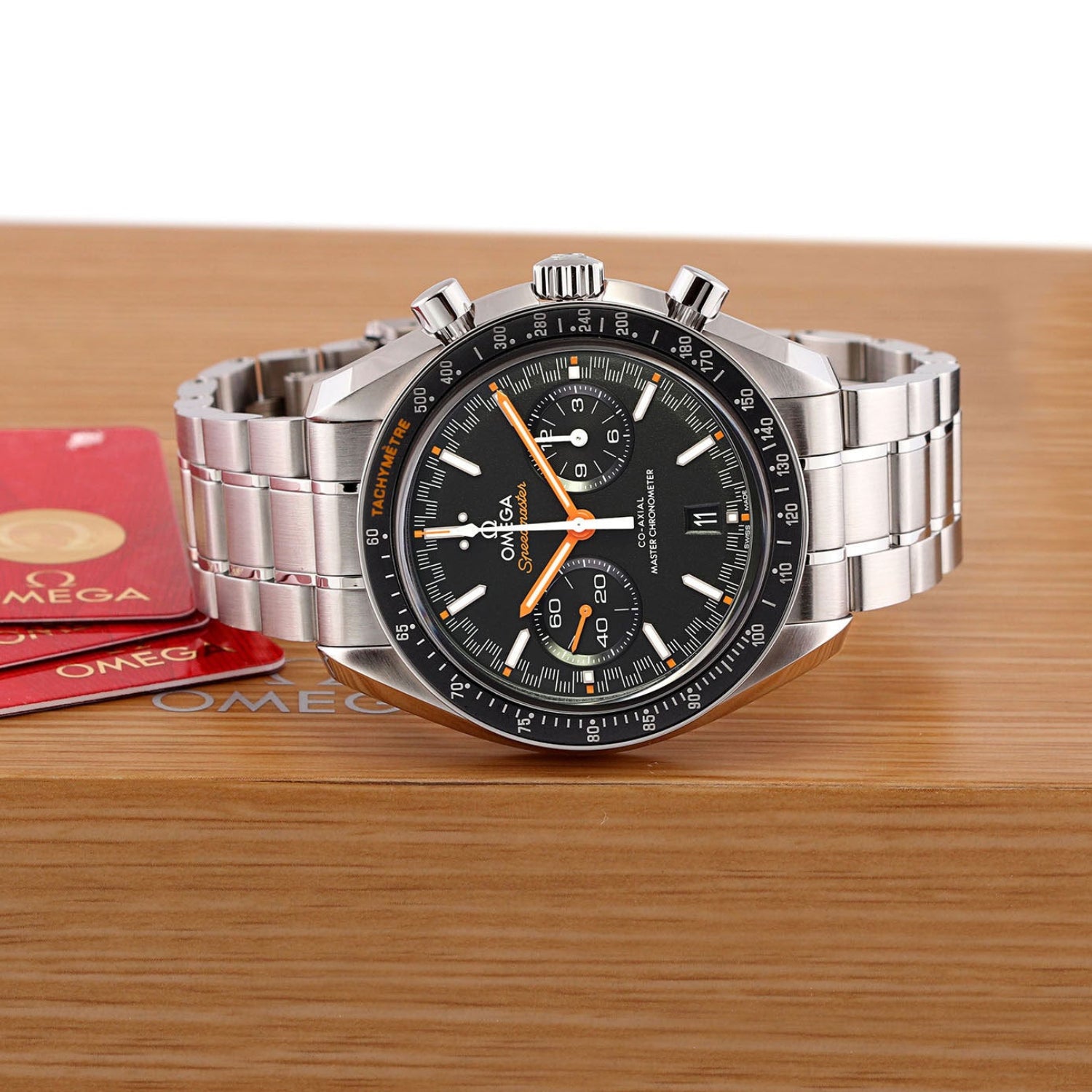 Silver Omega watch on a wooden surface with Omega packaging in the background