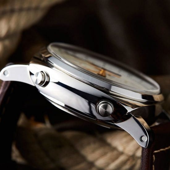 Close-up of a silver watch with a brown leather strap on a textured background
