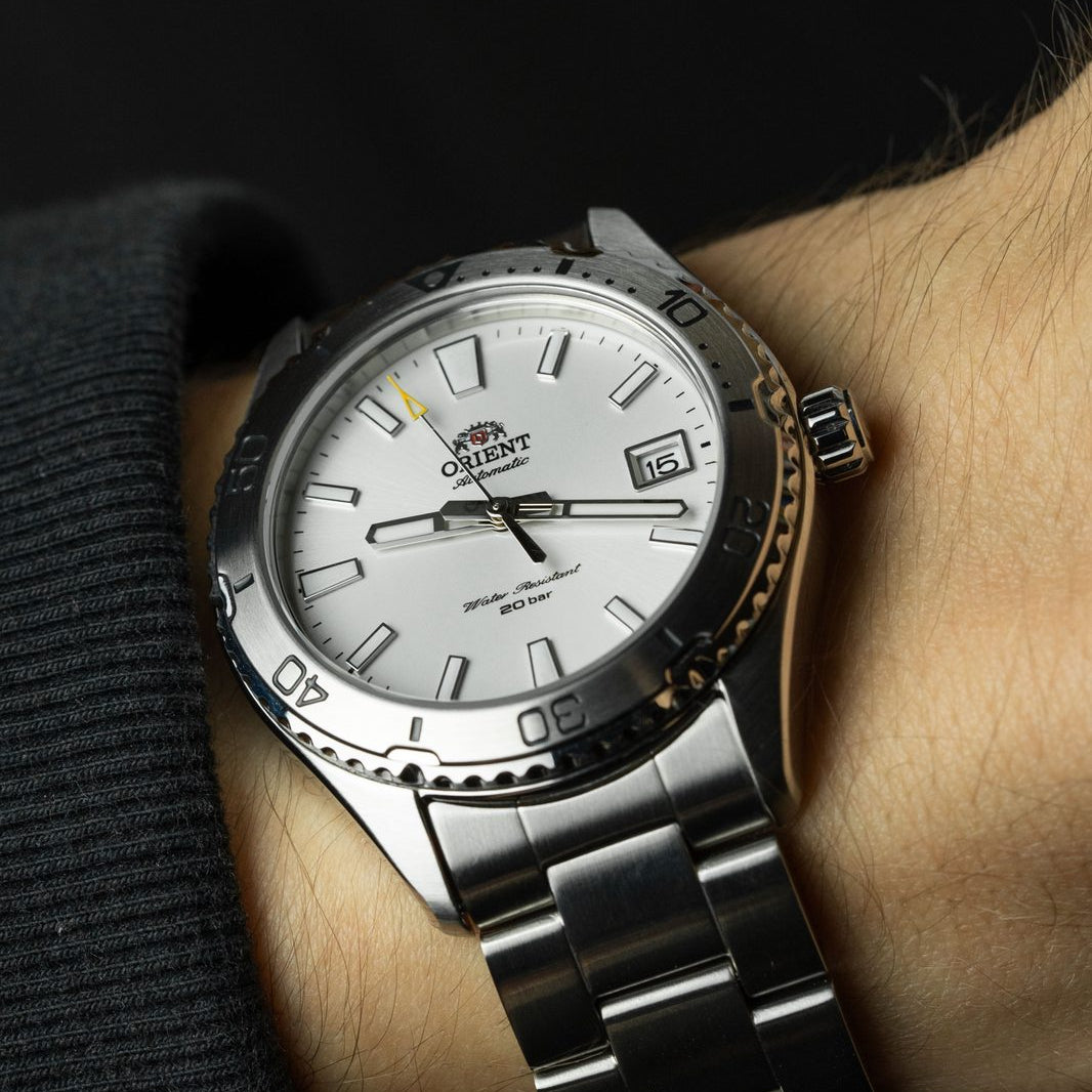 Silver wristwatch with a white face on a person's wrist against a dark background