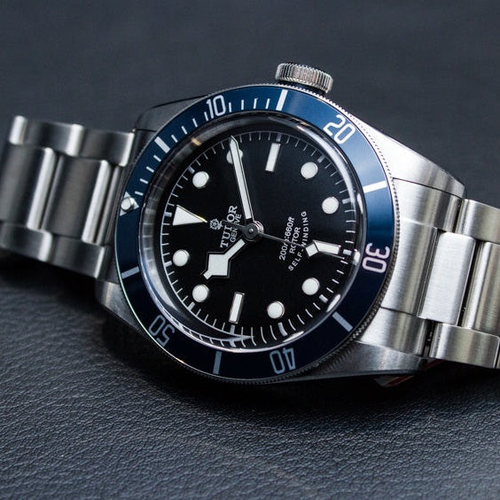 Silver watch with black dial on a dark gray background