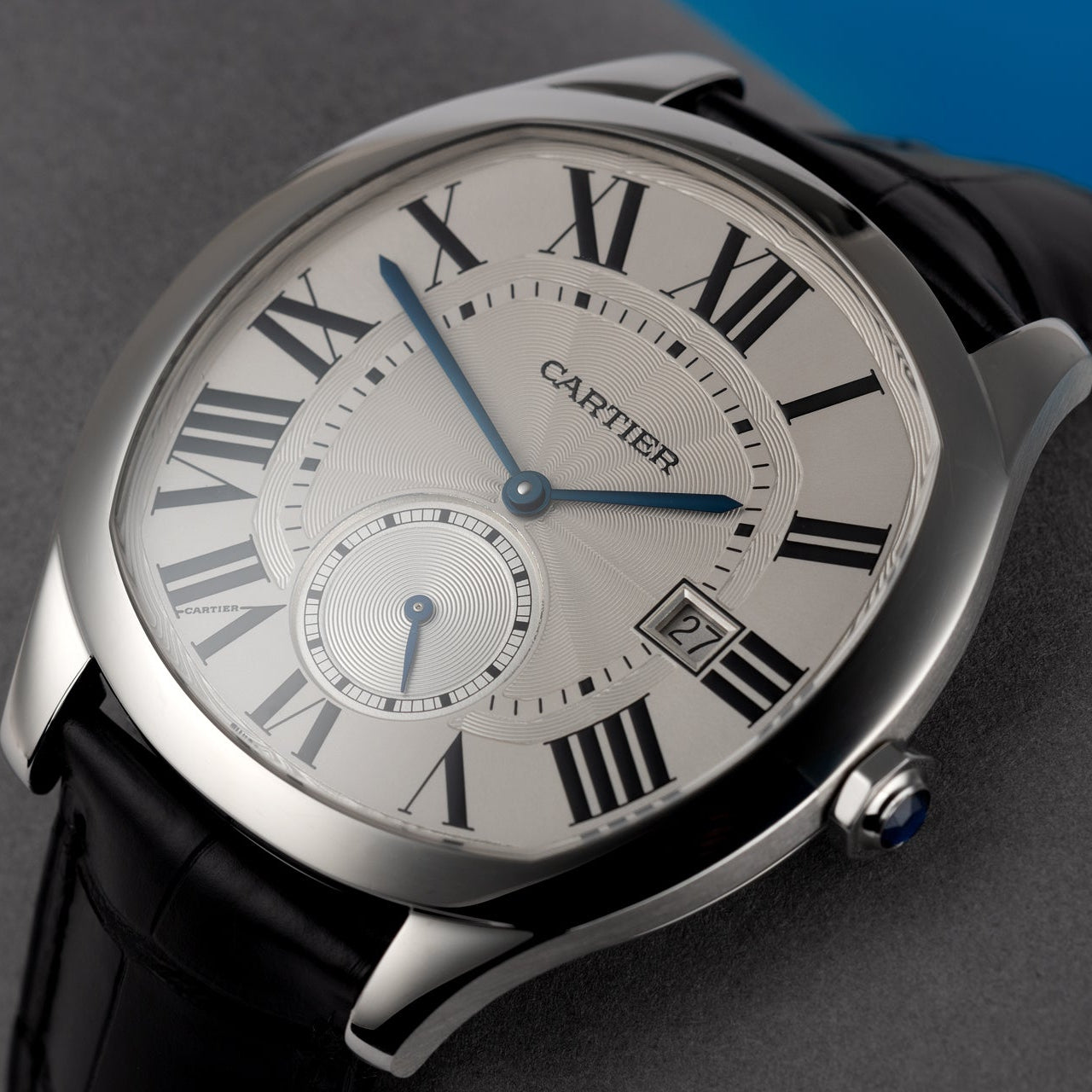 Cartier watch with black strap and silver case on a gray background