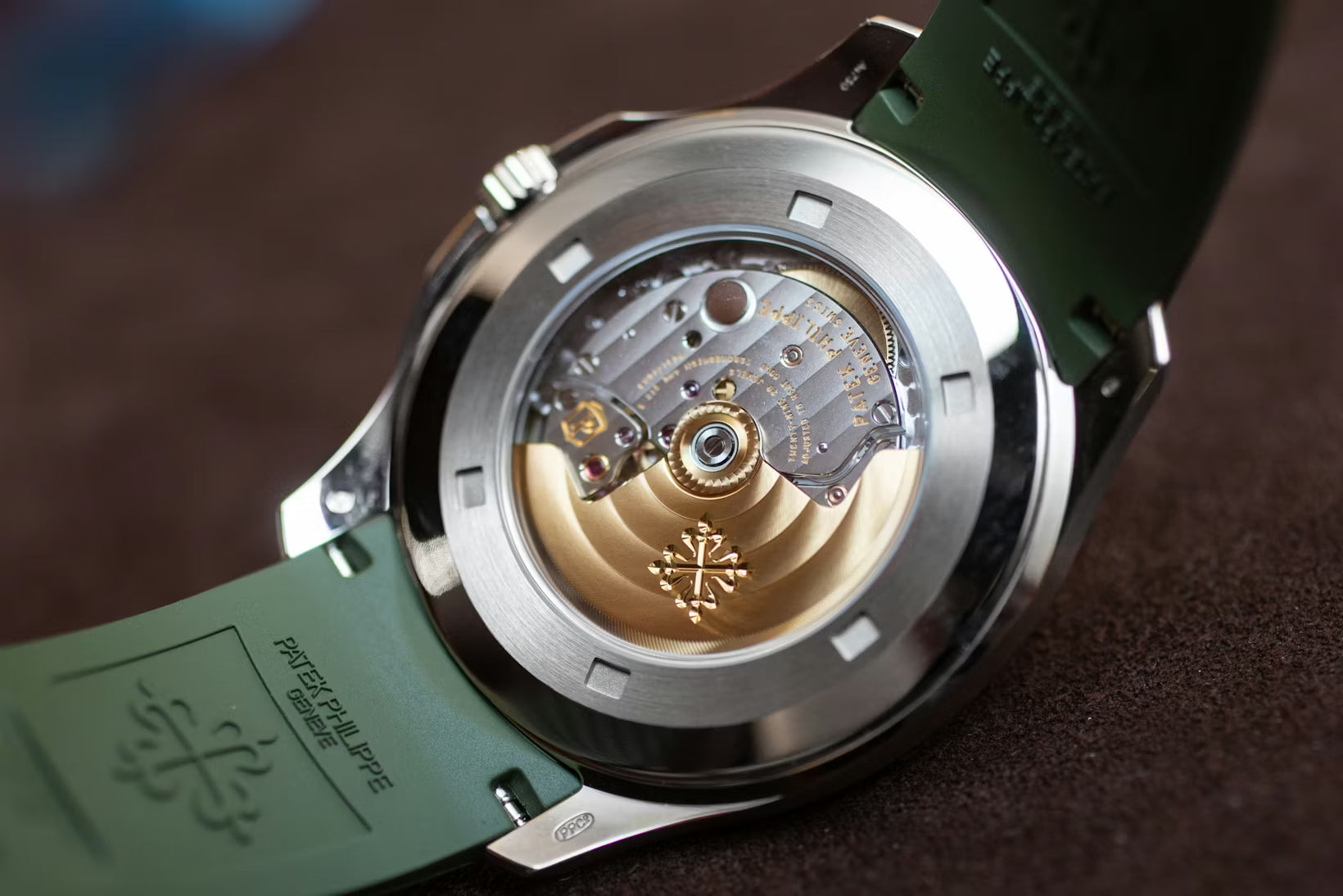 Close-up of a watch with a visible mechanical movement on a brown background