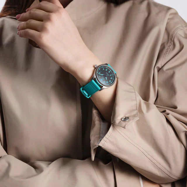 Person wearing a teal watch on a plain background