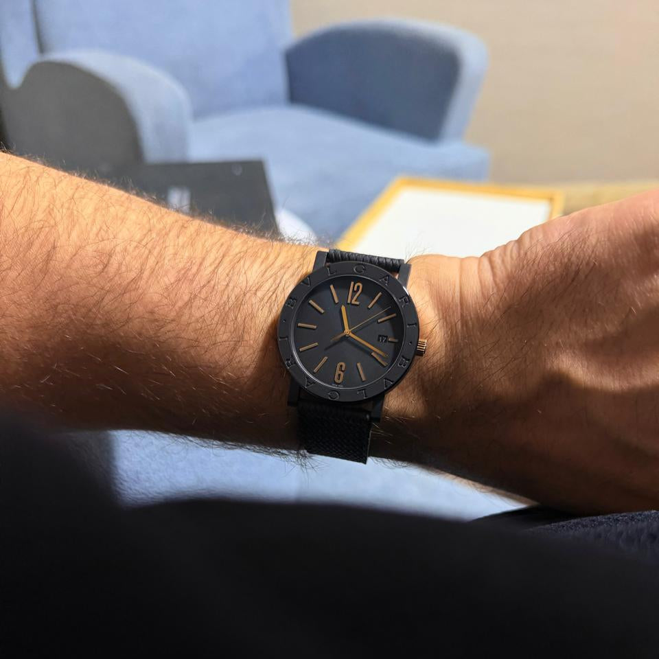 Black wristwatch on a person's wrist with a blurred background