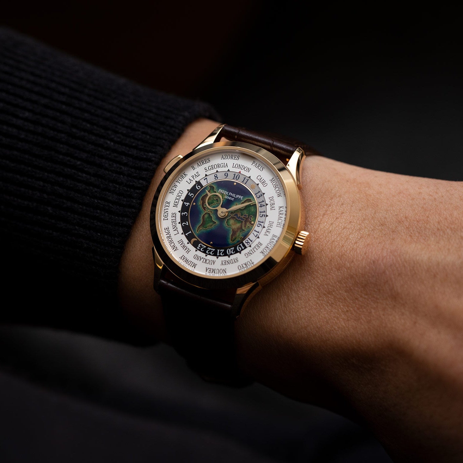 Gold wristwatch with a detailed face on a wrist against a dark background