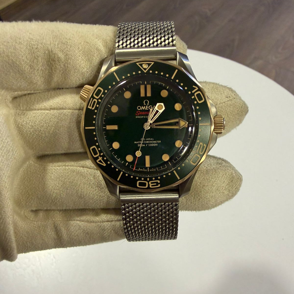 Gold and black watch on a mannequin hand with a wooden floor background