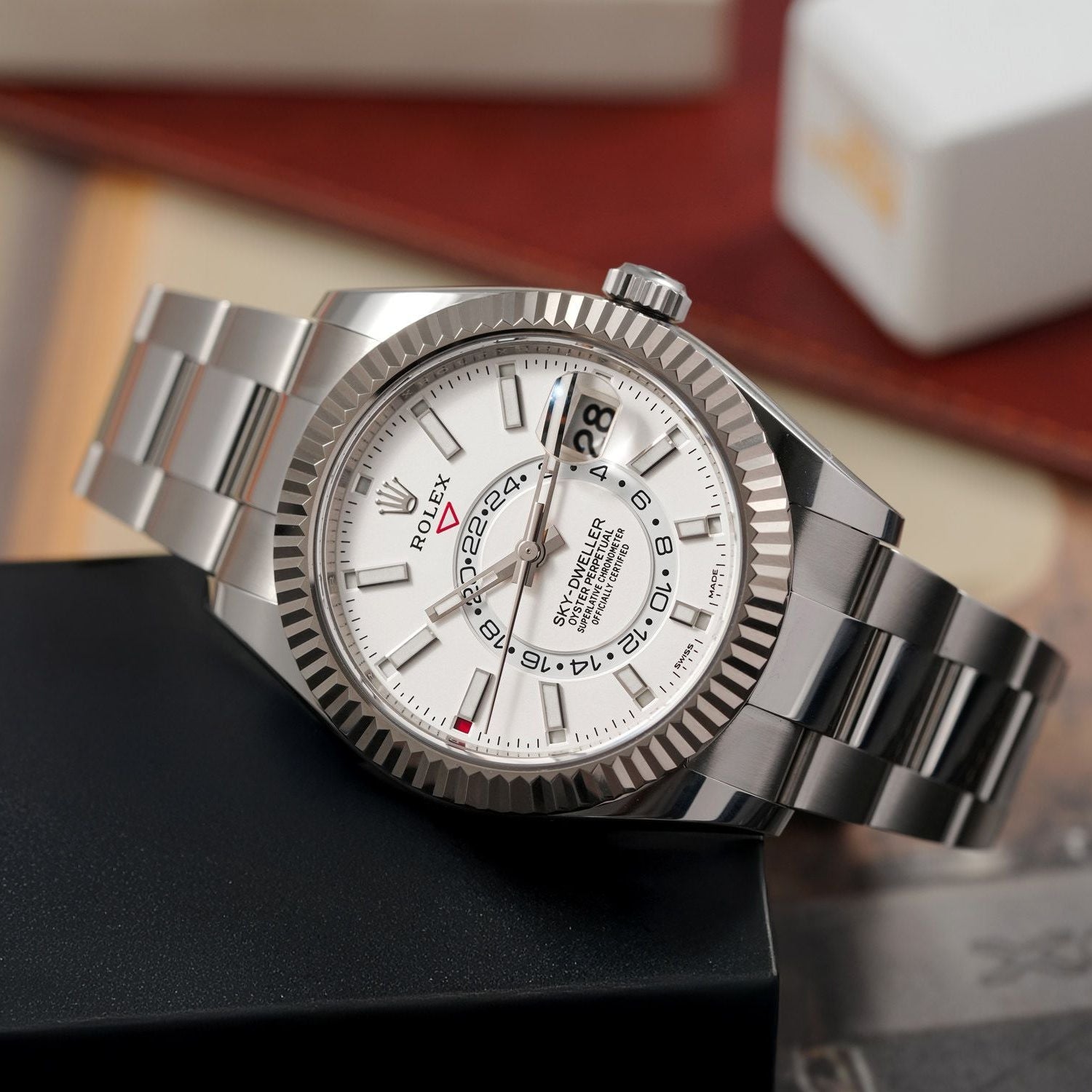 Silver Rolex watch on a dark surface with a blurred background