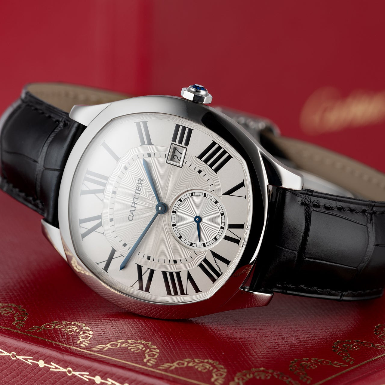 Luxury watch with black leather strap on a red surface